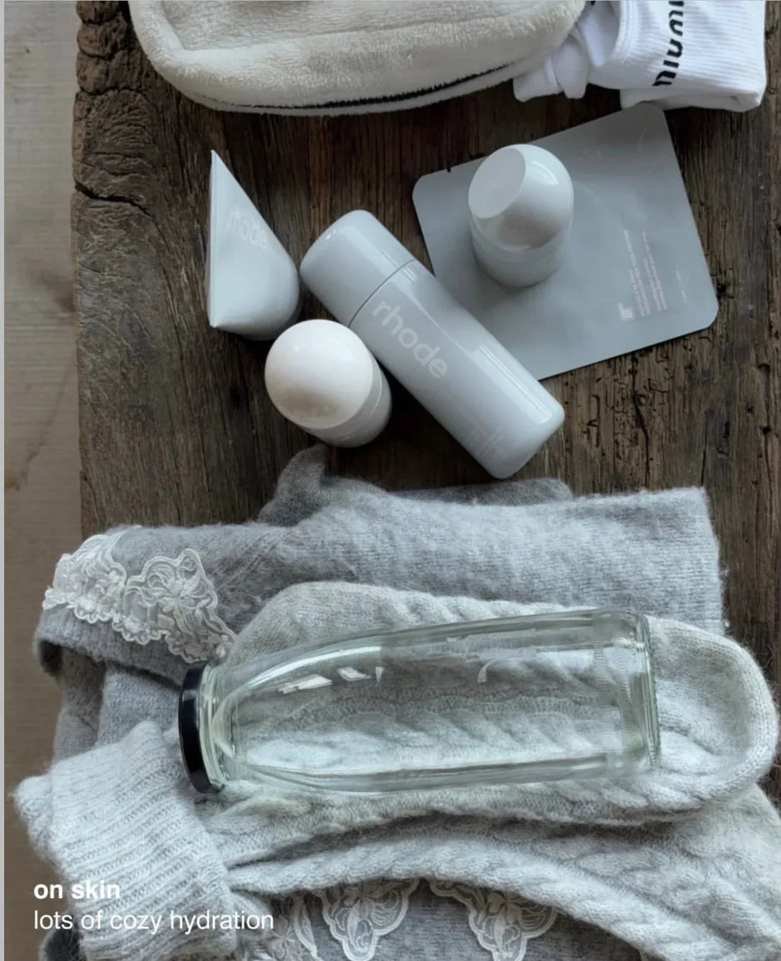 Luxurious grey skincare bottles and creamy texture products on soft knit fabric