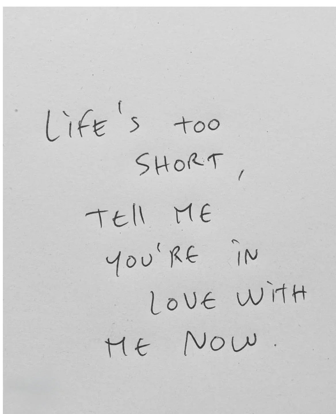 Minimalist handwritten note on white paper with inspiring quote about love and life.
