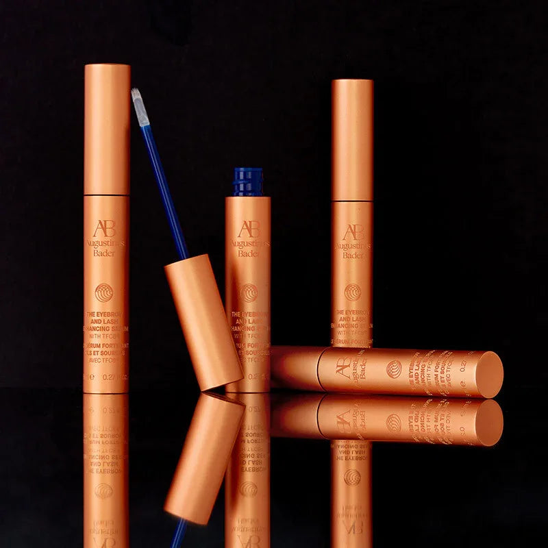 Luxurious copper eyebrow and lash serum tubes with sleek, metallic finish on black background.