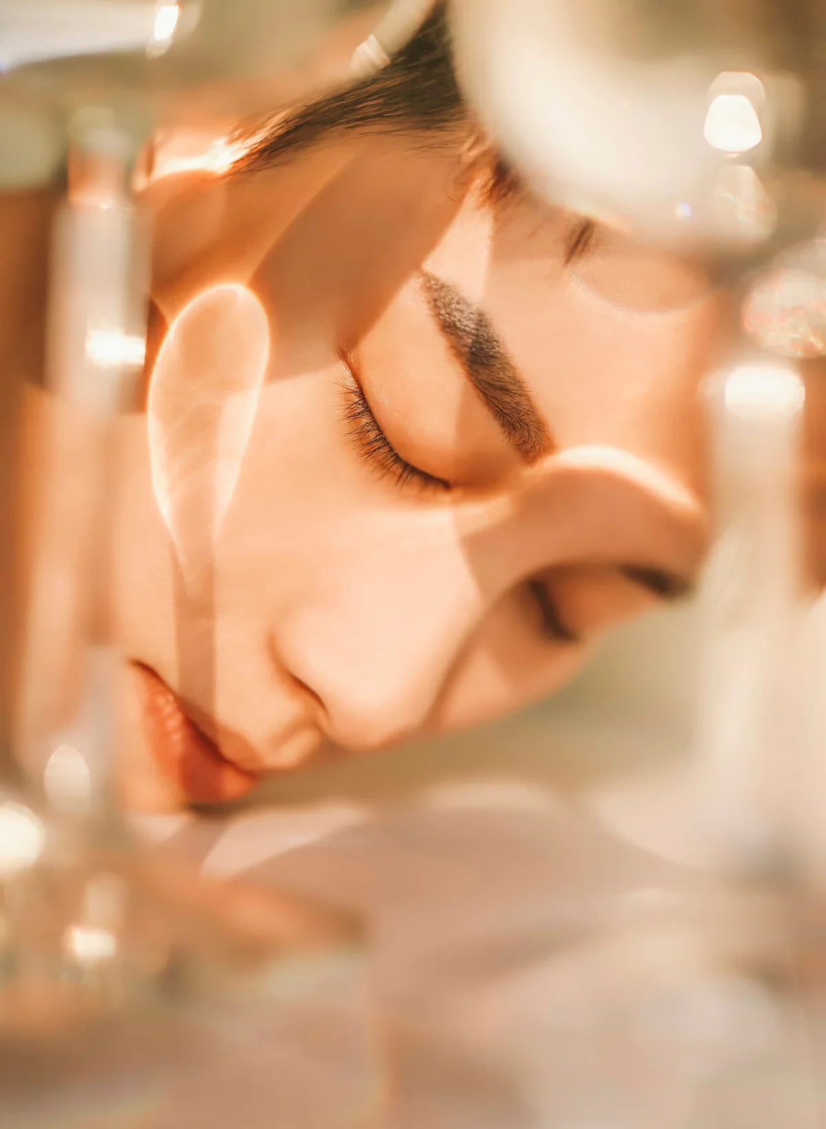 Close-up of glowing, dewy skin with soft golden tones and natural makeup in dreamy light.
