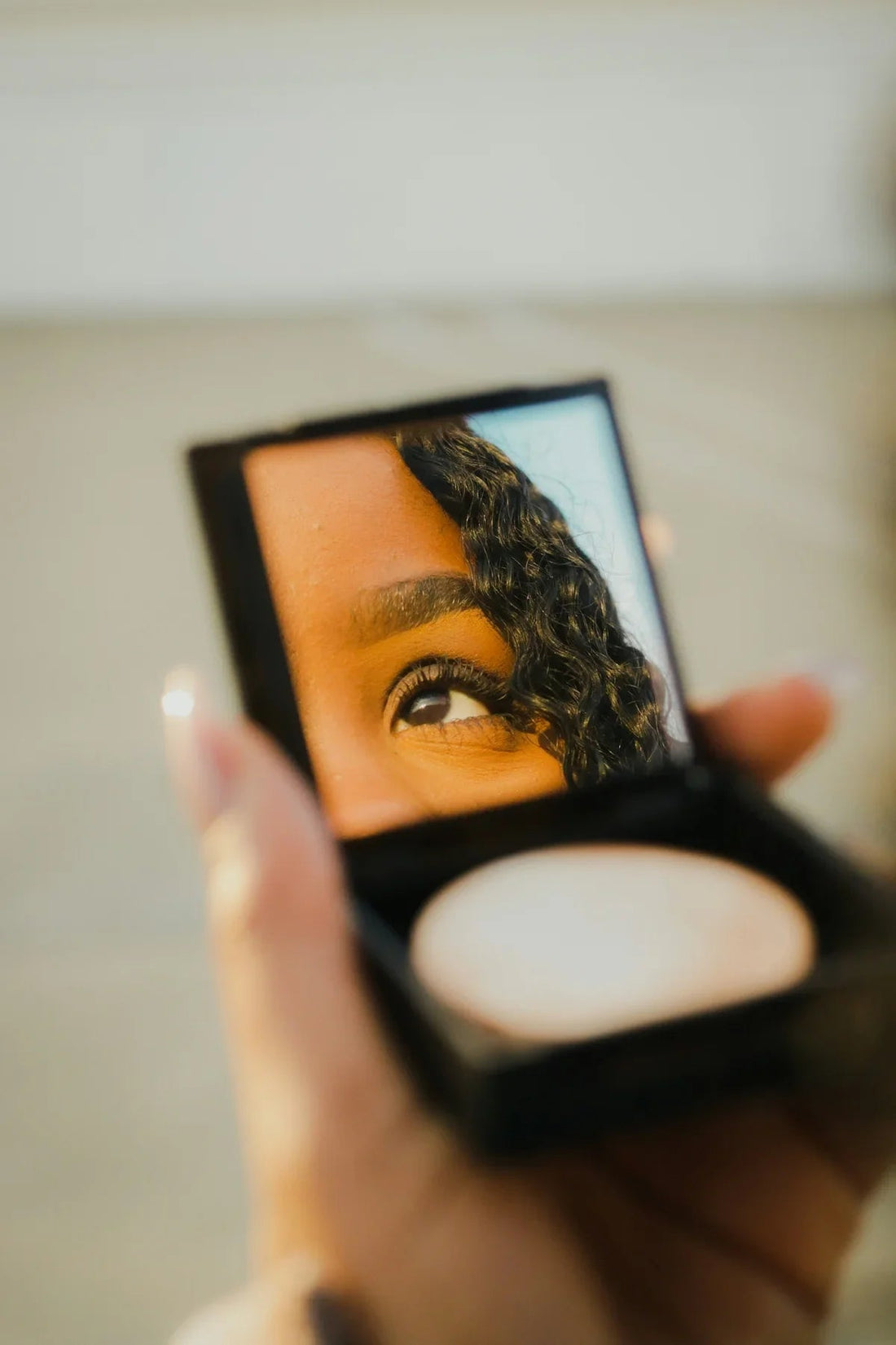 Elegant compact powder with soft, matte texture reflected in makeup mirror, warm tones