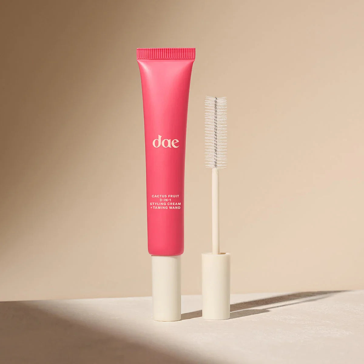 Pink cactus fruit styling cream with creamy texture and beige taming wand on a neutral background