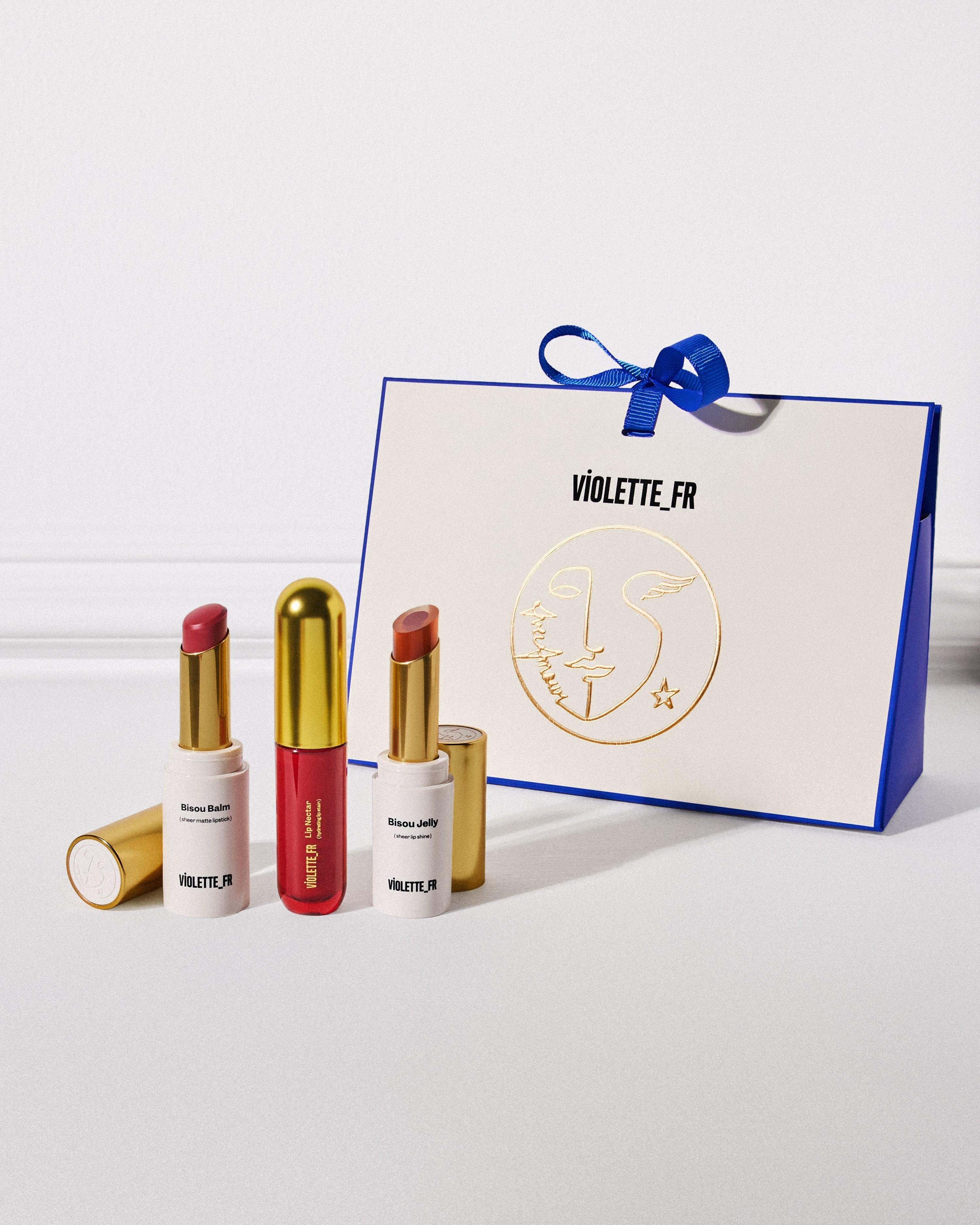 Violette_FR gift bag with Bisou Balm, Bisou Jelly lip products, and lip lacquer displayed on a white surface