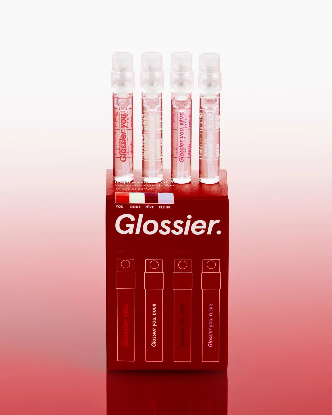 Elegant set of four Glossier mini perfume sprays in clear bottles on a glossy red box.