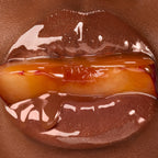 Close up of glossy lips holding a plum.
