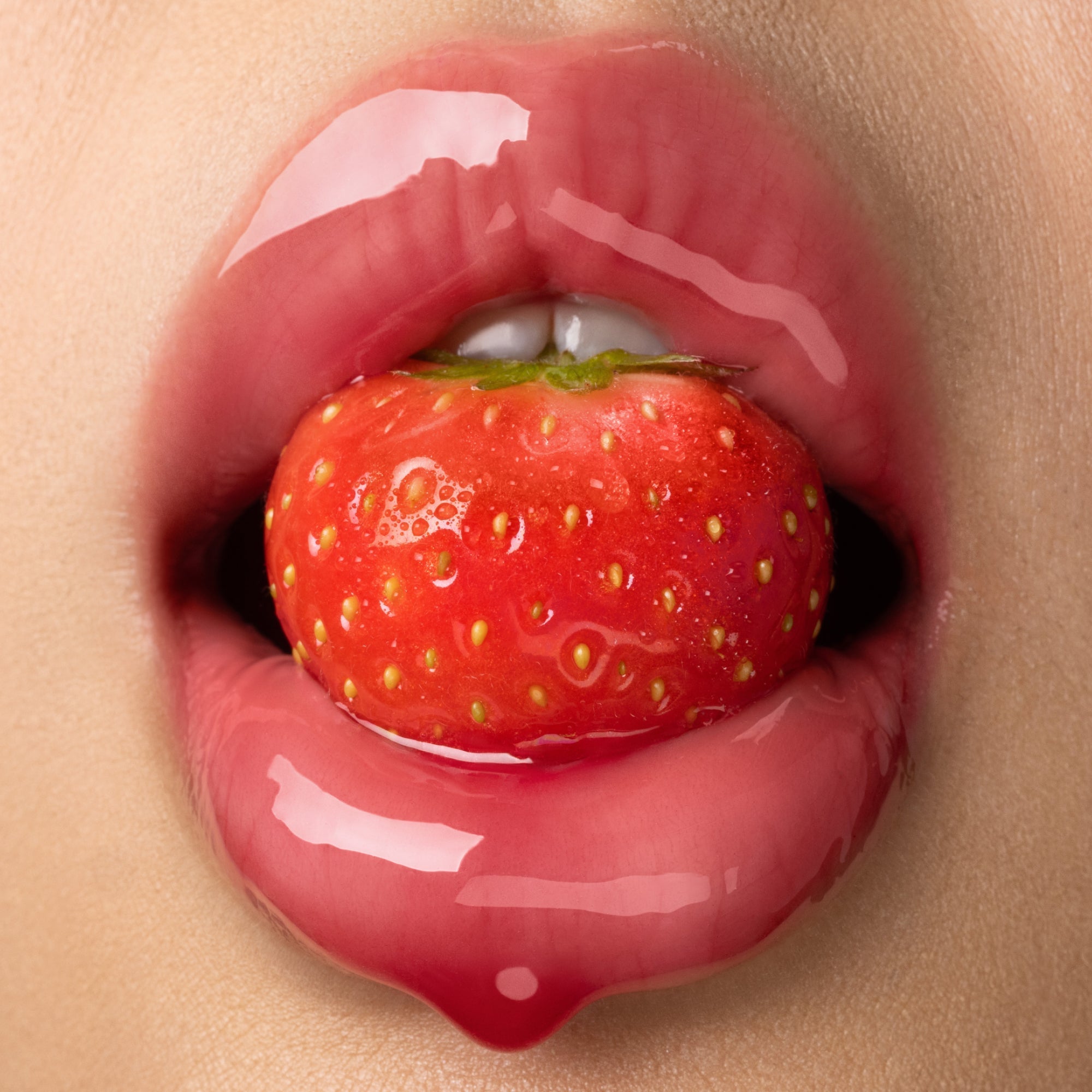 Glossy lips holding a strawberry.