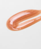 Shimmery peach lip gloss smear on white background, makeup product closeup