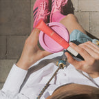 Woman holding Dae beauty tube with pink coffee cup, Wylde Grey skincare, outdoor lifestyle