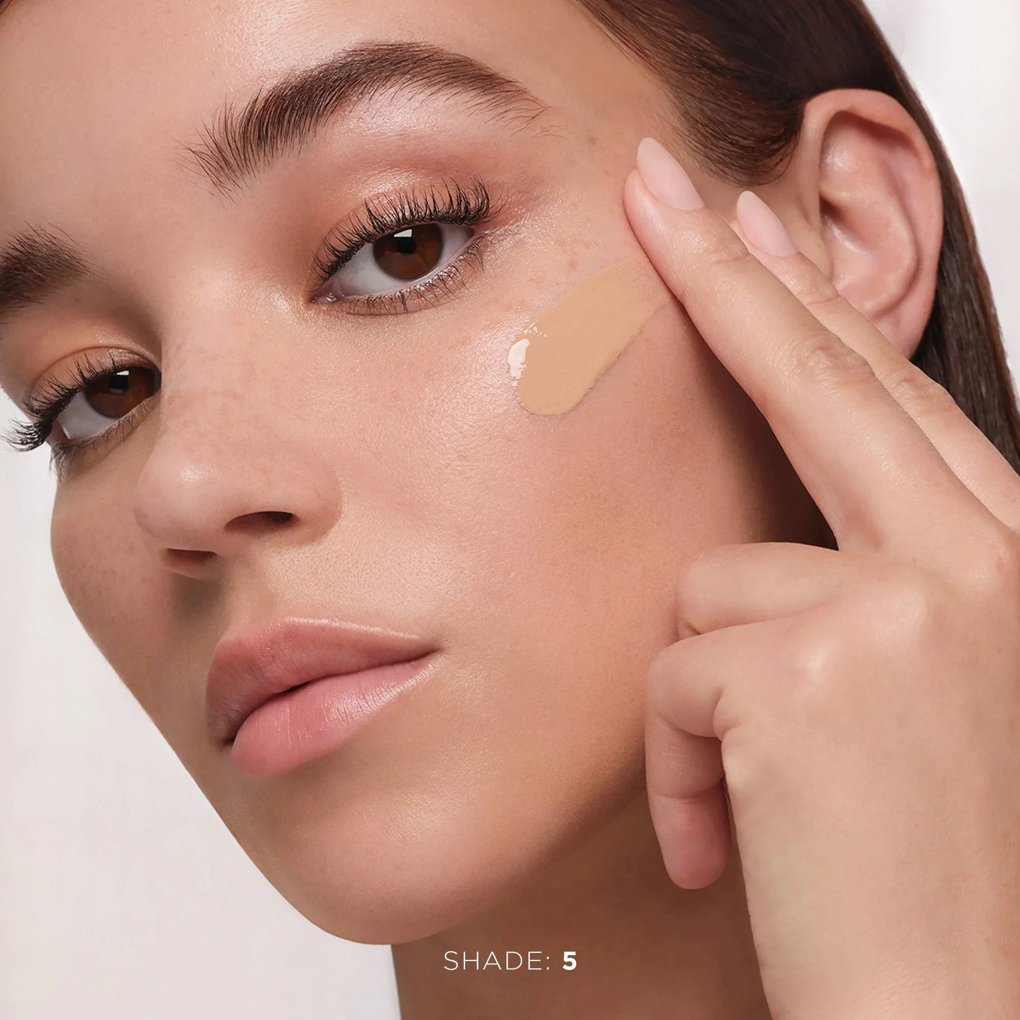Model applying creamy beige liquid foundation, dewy finish, beauty skincare, Shade 5