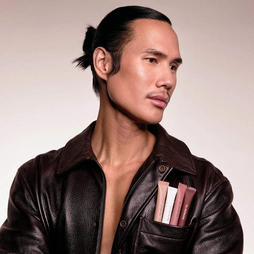 Man in brown leather jacket with radiant skin, holding neutral-toned beauty tubes in pocket