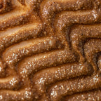 Closeup of a shimmering, golden-brown textured face mask with exfoliating grains