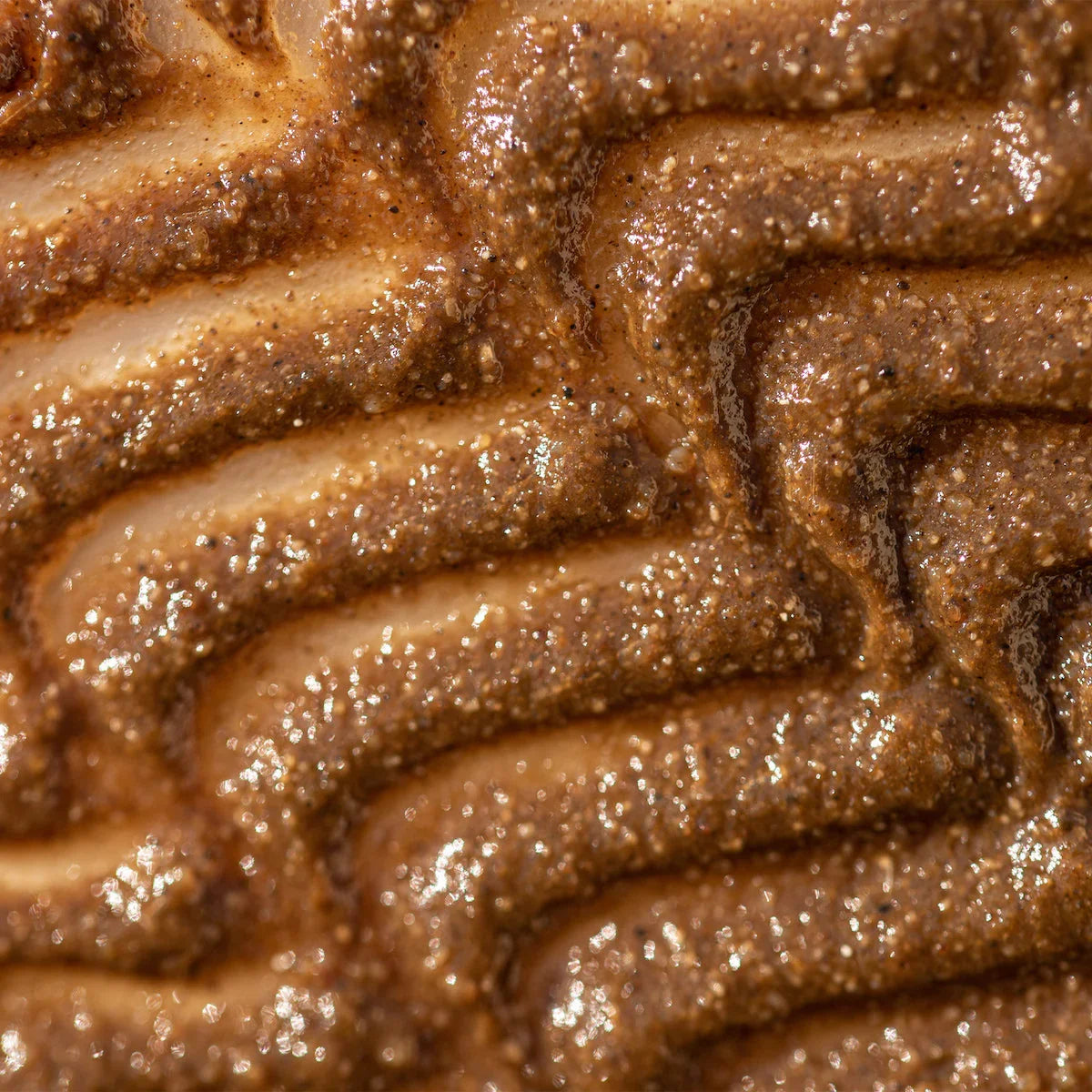 Closeup of a shimmering, golden-brown textured face mask with exfoliating grains