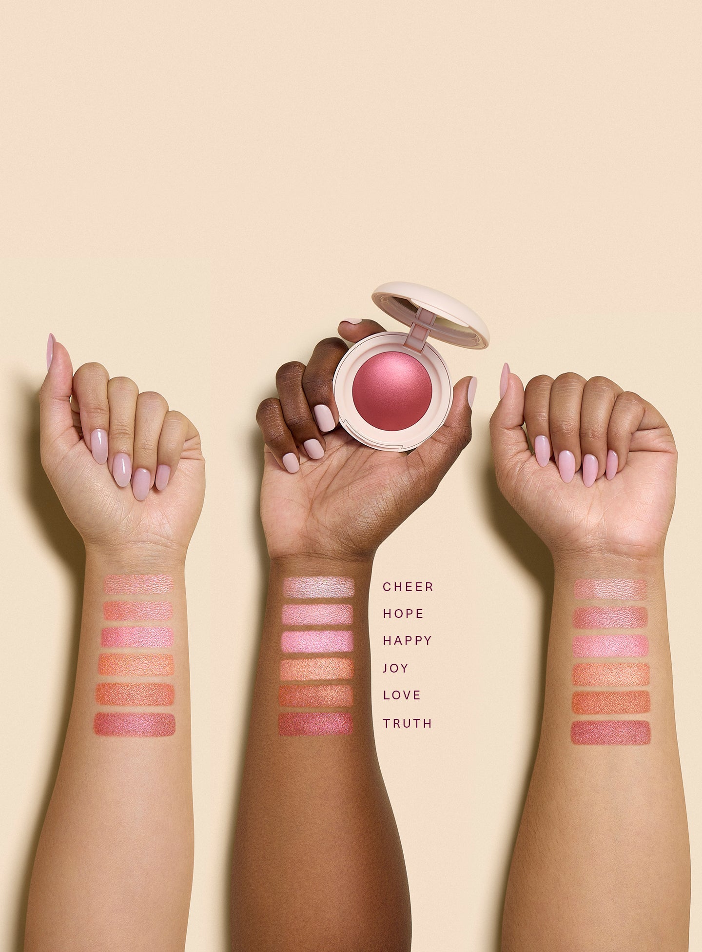 | Swatches of all shades of Rare Beauty's Soft Pinch Luminous Powder Blush on three arms of varying skin tones. The center hand holds the product.