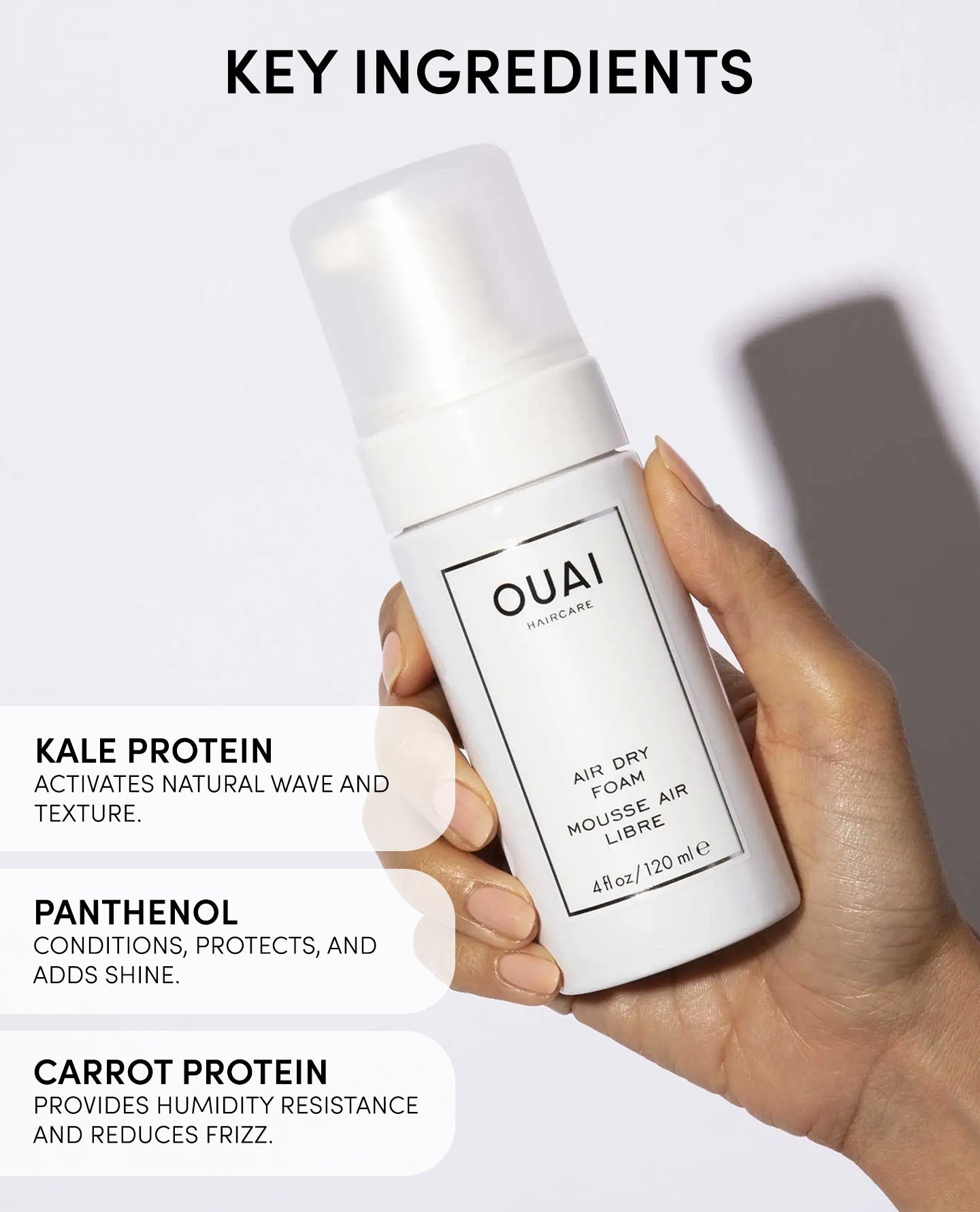 OUAI hair product held by a hand with key ingredients listed on a white background