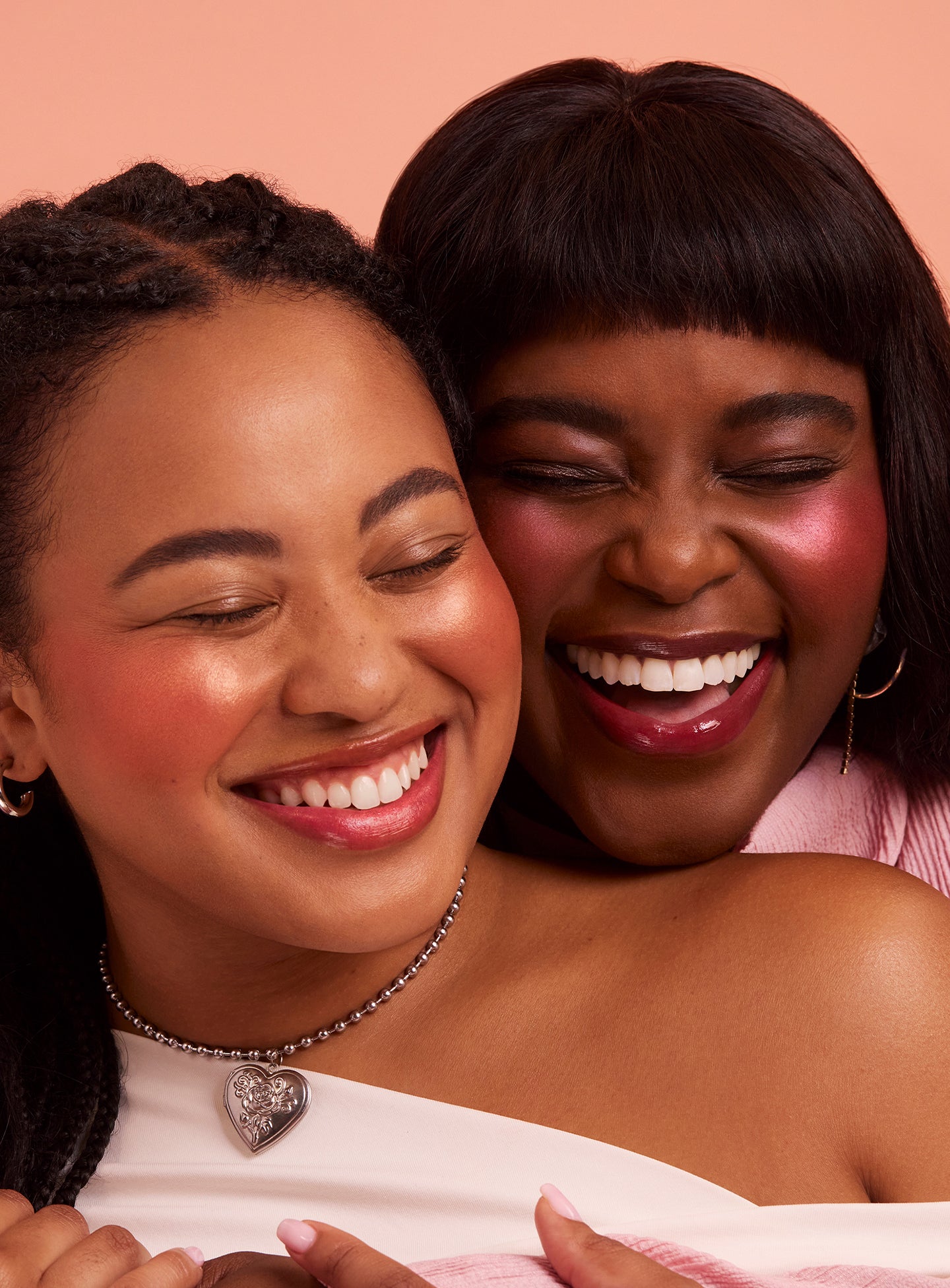 | Two models smile and embrace while wearing Rare Beauty's Soft Pinch Luminous Powder Blush.
