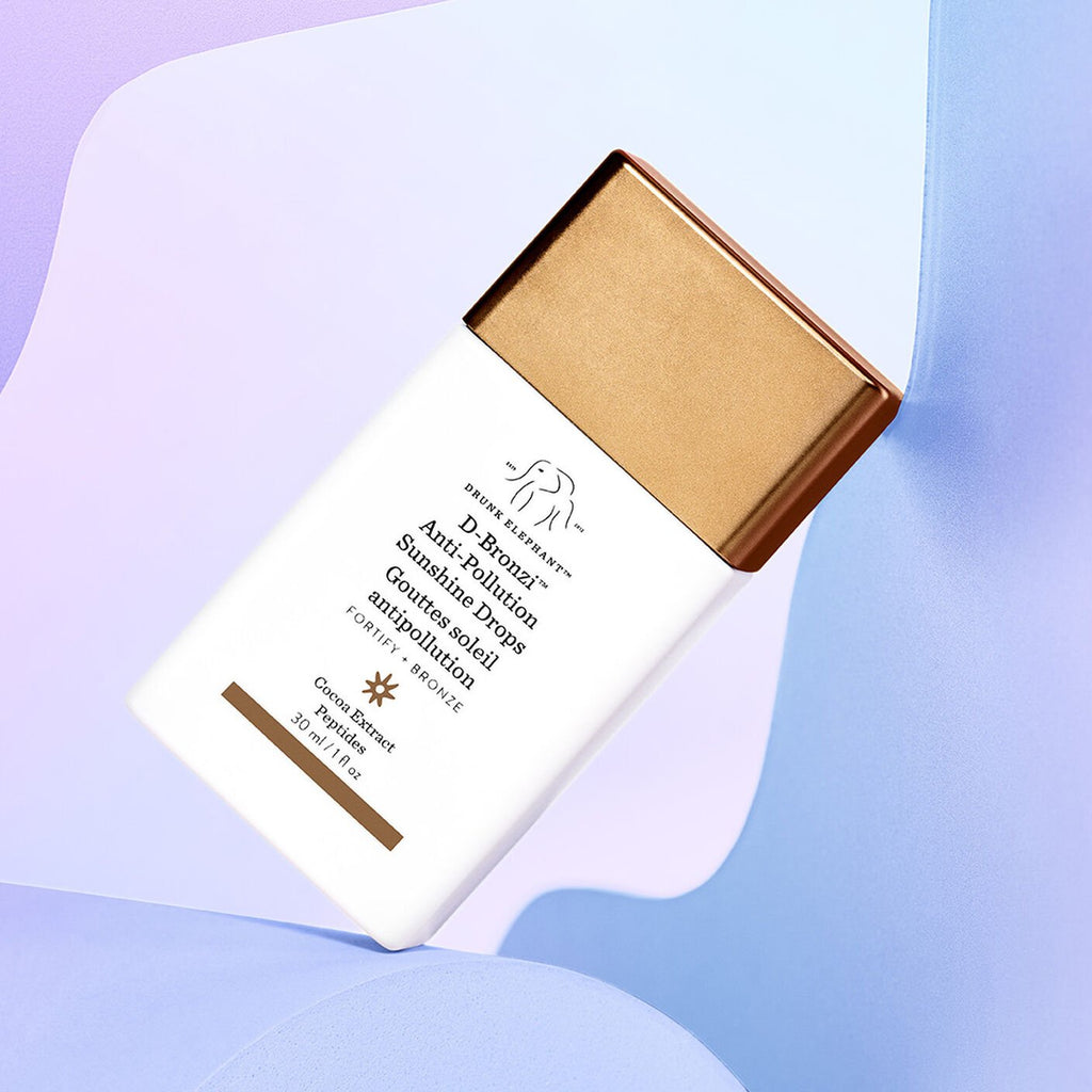 Drunk Elephant D-Bronzi Anti-Pollution Sunshine Drops bottle on pastel abstract background