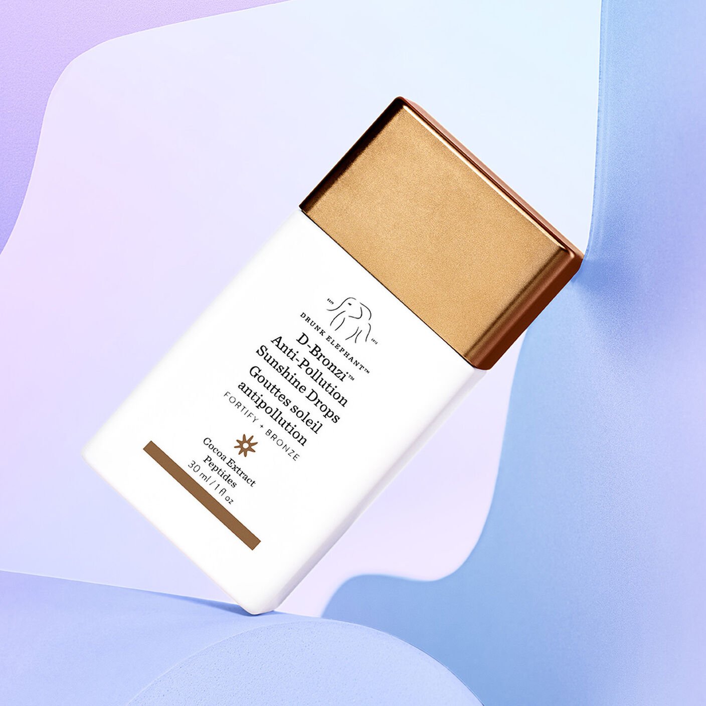 Drunk Elephant D-Bronzi Anti-Pollution Sunshine Drops bottle on pastel abstract background