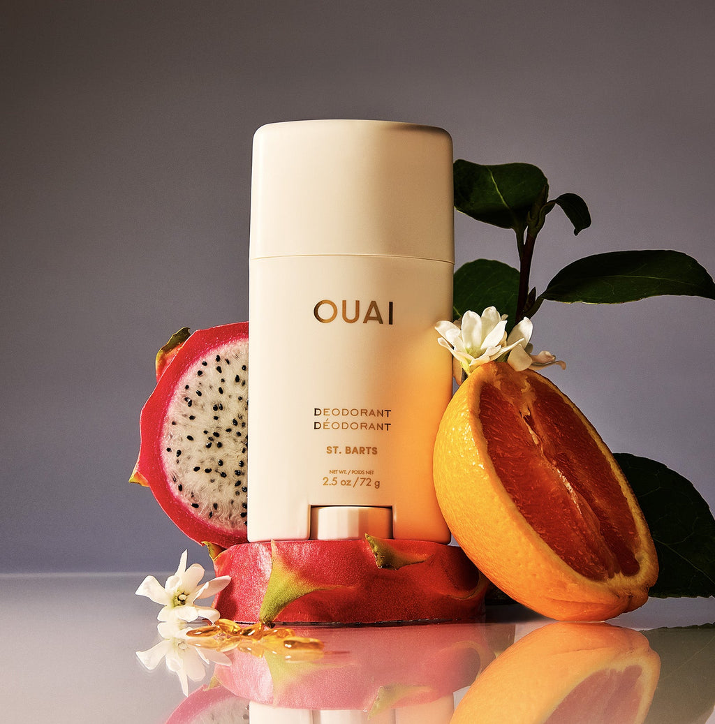OUAI deodorant bottle with dragon fruit and orange on a reflective surface