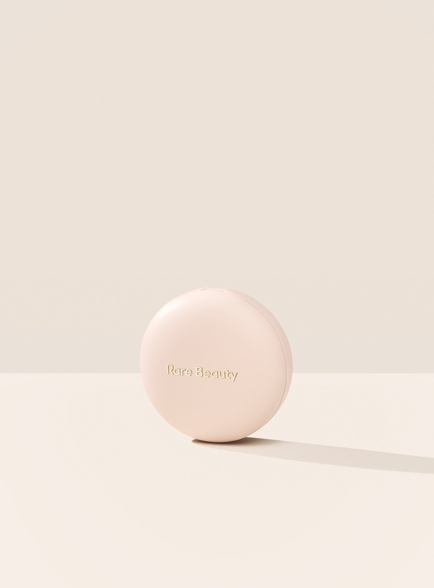 | The exterior of Rare Beauty's Soft Pinch Luminous Powder Blush is displayed with its simple neutral pink case and "Rare Beauty" etched on the outside.