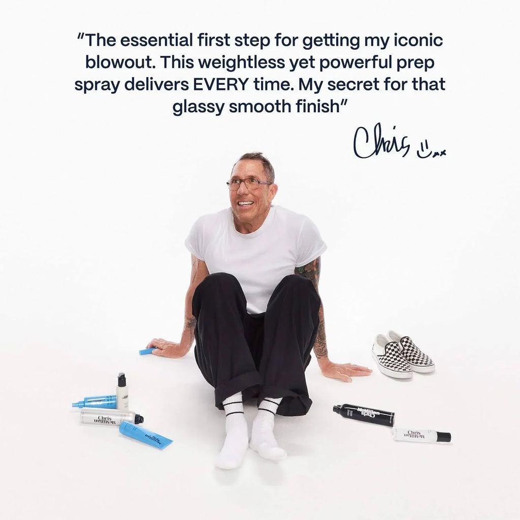 Man in white shirt and black pants sits on white background with luxe haircare products and stylish slip-on shoes, promoting smooth, glassy finish beauty essentials.