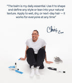 Man in white tee and black pants sitting with Chris Appleton hair products, minimalist white background, Wylde Grey beauty.