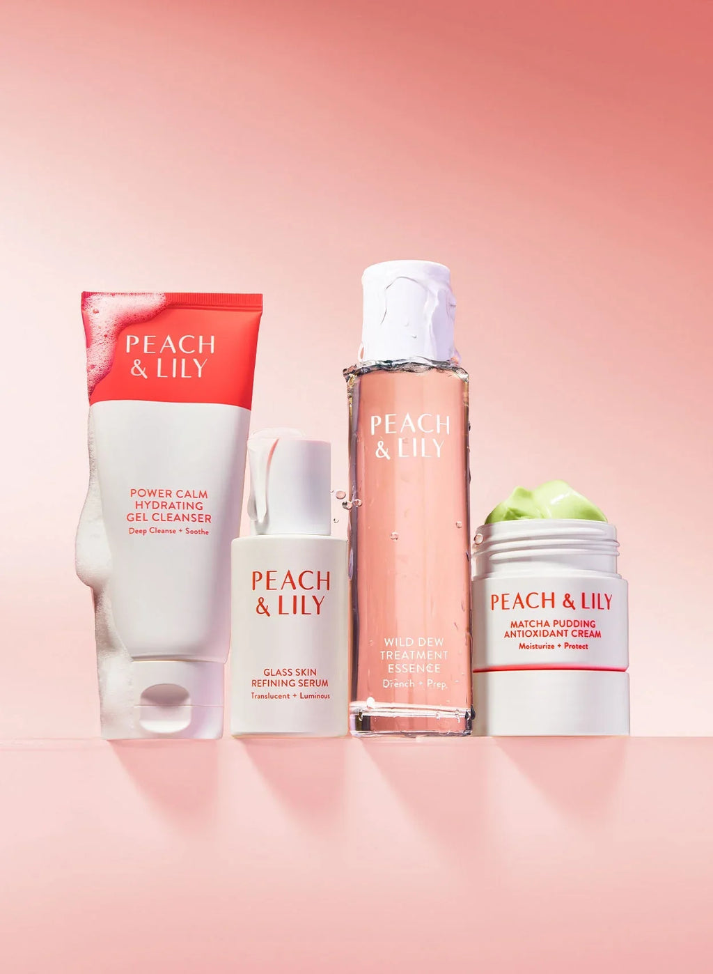 Peach & Lily skincare set with hydrating gel cleanser, serum, essence, and green cream on a pink background, highlighting luxurious and dewy textures.
