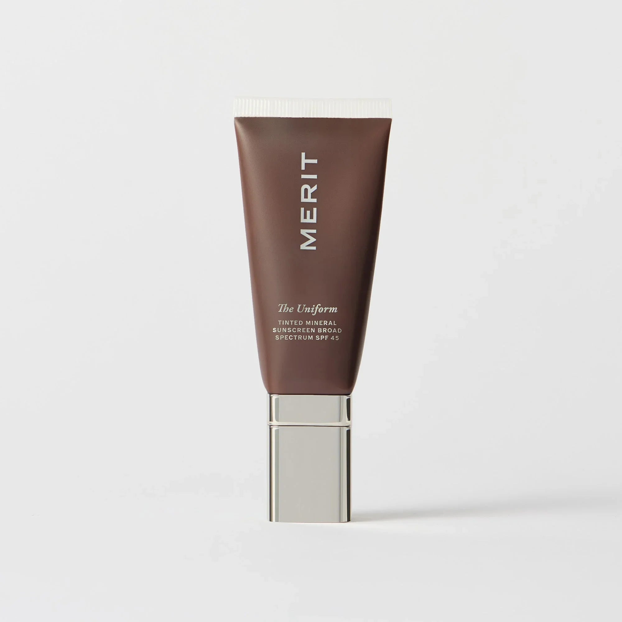 Master || A tube of MERIT brand mineral sunscreen with a sheer tint finish, providing broad spectrum 45 UVA/UVB protection, displayed against a white background. Shade 02