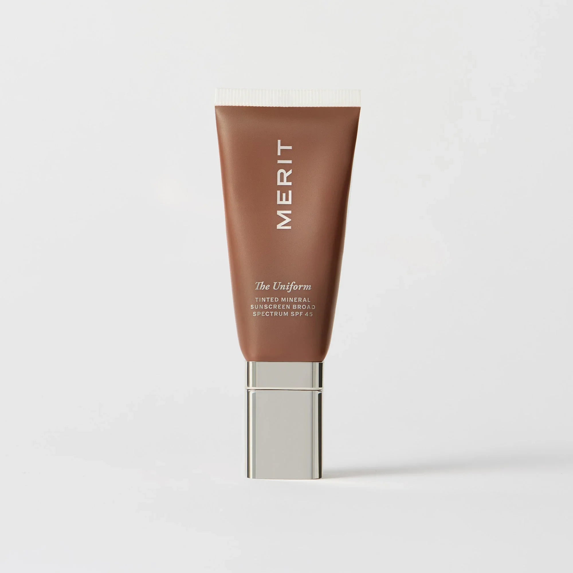 Master || A tube of MERIT brand mineral sunscreen with a sheer tint finish, providing broad spectrum 45 UVA/UVB protection, displayed against a white background.