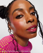 Close-up of woman with braided hair wearing pink and yellow polka dot top and bold pink jelly tint makeup