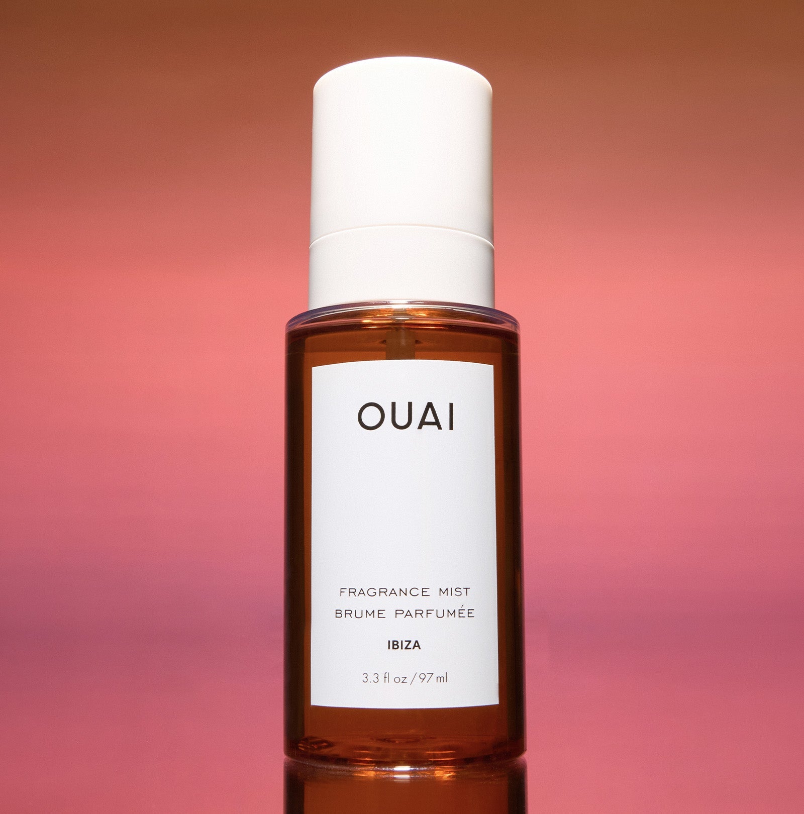 OUAI fragrance mist bottle on a gradient pink background