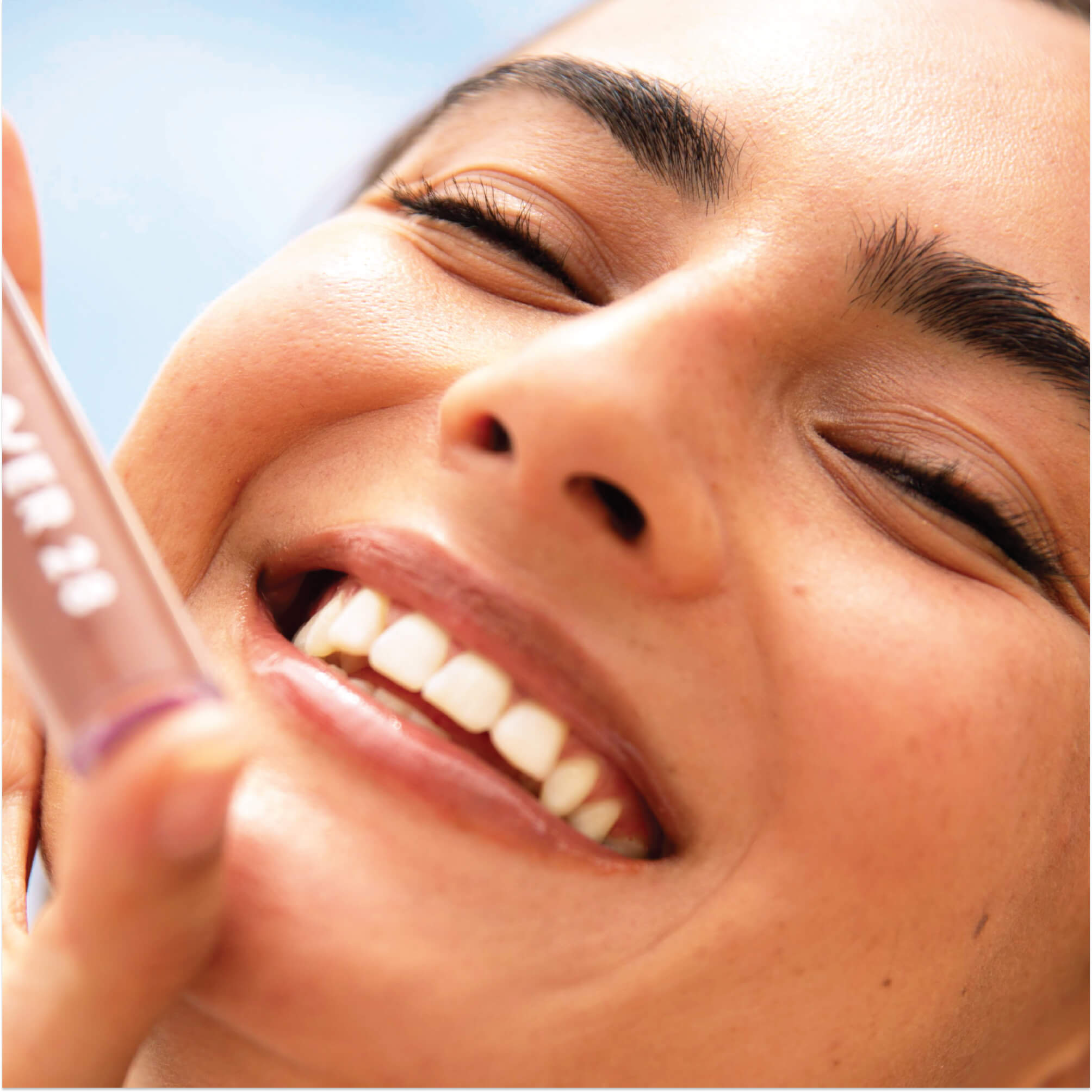 A model wearing the Tower 28 Beauty ShineOn Lip Jelly in the shade Almond on her lips. [Almond]