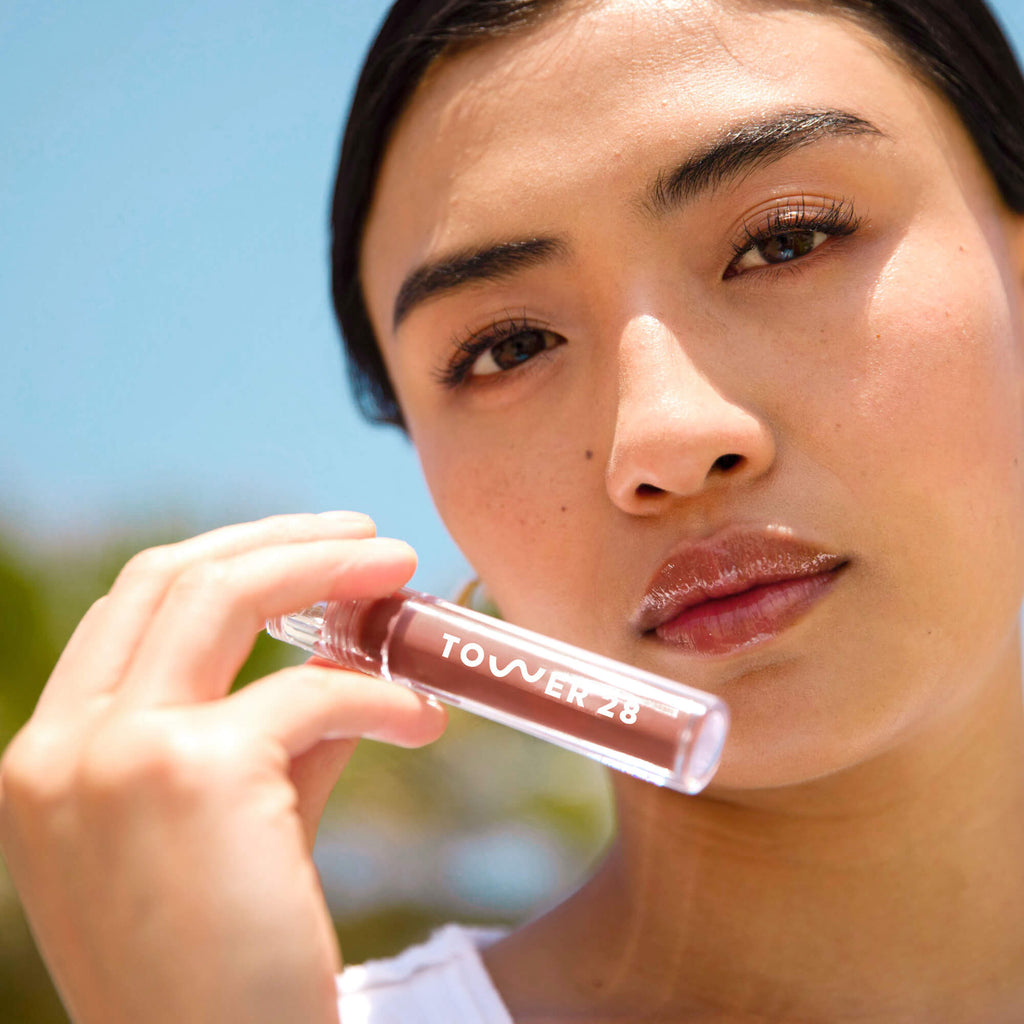 A model wearing the Tower 28 Beauty ShineOn Lip Jelly in the shade Almond on her lips. [Almond]