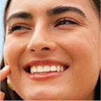 A model wearing the Tower 28 Beauty ShineOn Lip Jelly in the shade Cashew on her lips. [Cashew]