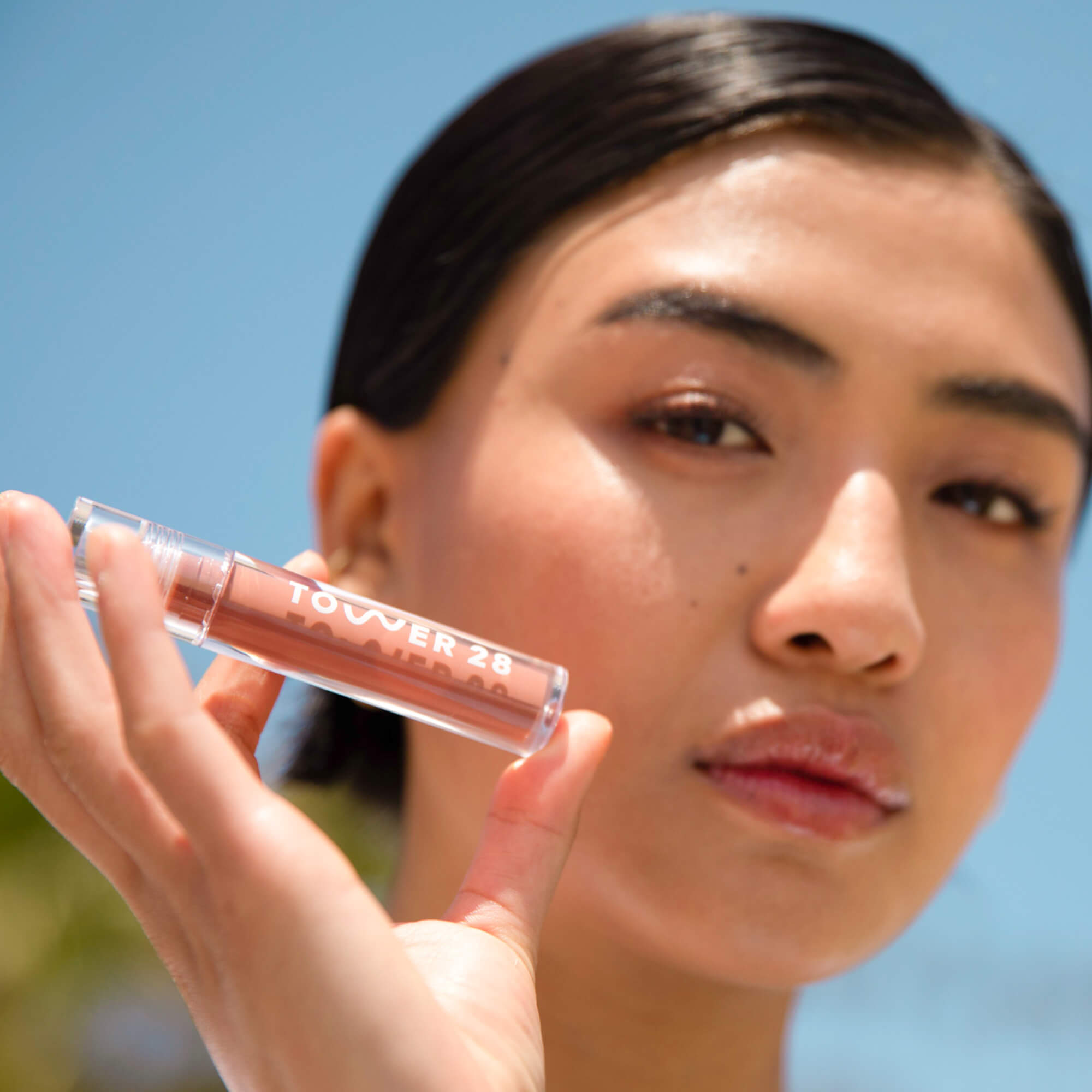 A model wearing the Tower 28 Beauty ShineOn Lip Jelly in the shade Cashew on her lips. [Cashew]