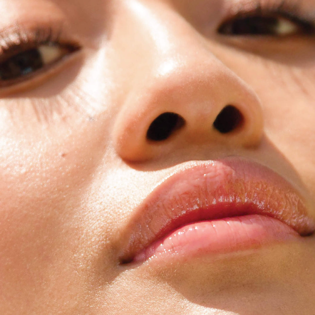 A model wearing the Tower 28 Beauty ShineOn Lip Jelly in the shade Oat on her lips. [Oat]