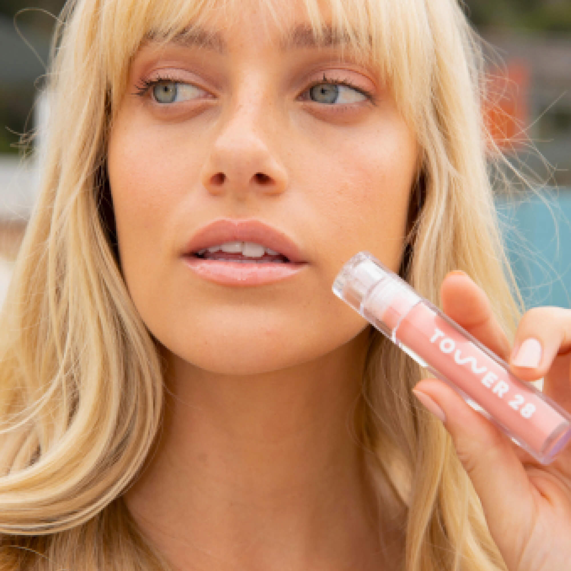 A model wearing the Tower 28 Beauty ShineOn Lip Jelly in the shade Oat on her lips. [Oat]