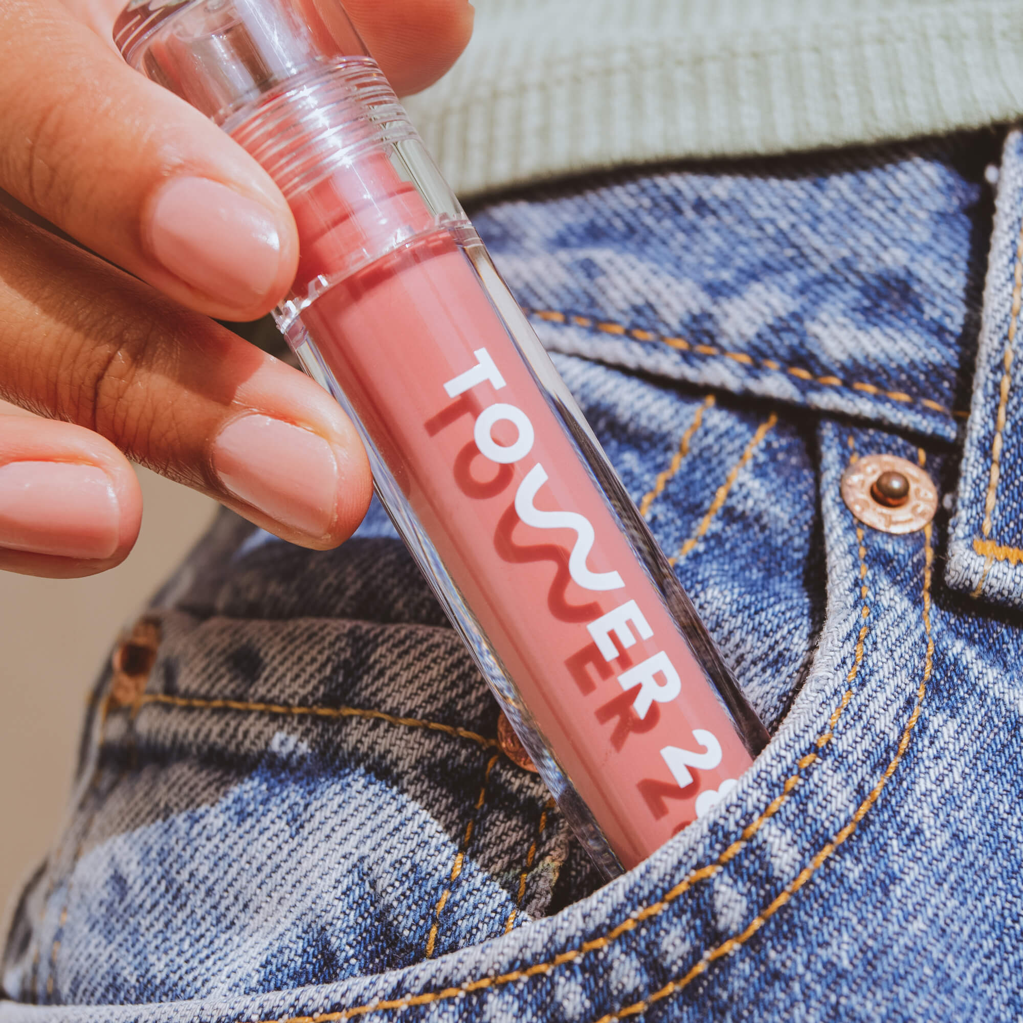 A model holding the Tower 28 Beauty ShineOn Lip Jelly in the shade Pistachio in her hands. [Pistachio]