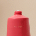 Vibrant coral tube squeezing creamy skincare on beige background, Wylde Grey beauty essentials