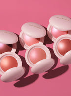 | All six shades of Rare Beauty's Soft Pinch Luminous Powder Blush lay on a pink background.