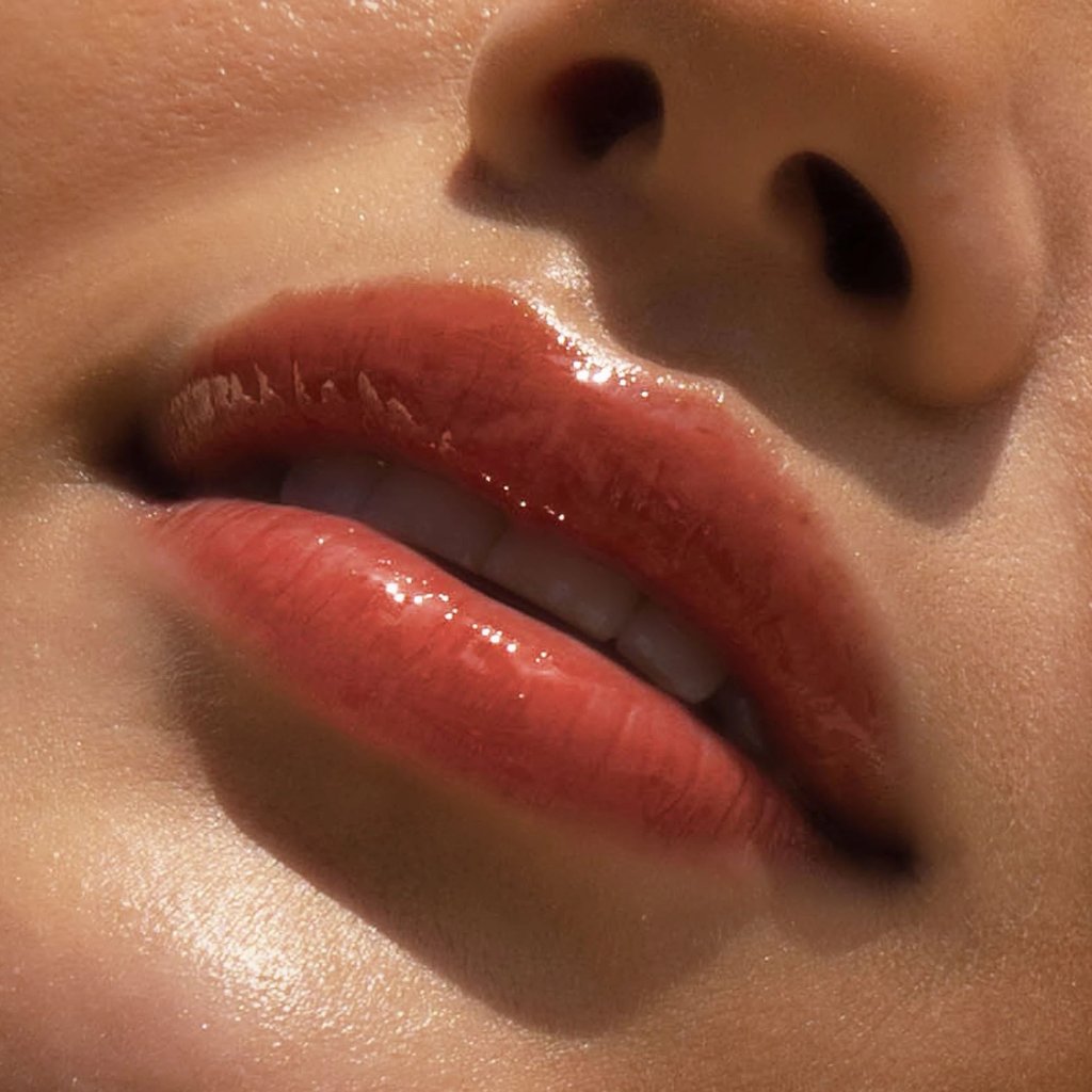 A model wearing the Tower 28 Beauty ShineOn Lip Jelly in the shade Fire on her lips. [Fire]
