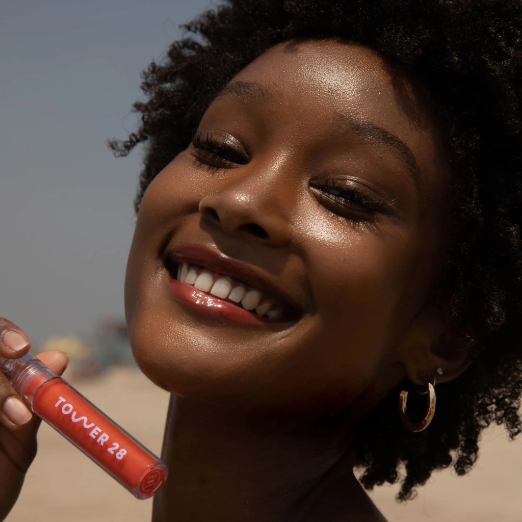 A model wearing the Tower 28 Beauty ShineOn Lip Jelly in the shade Fire on her lips. [Fire]