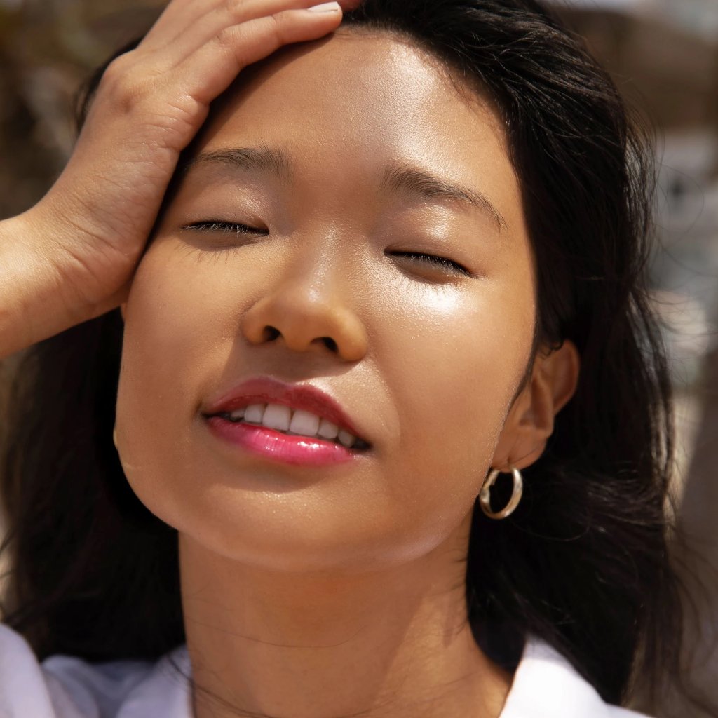 A model wearing the Tower 28 Beauty ShineOn Lip Jelly in the shade XOXO on her lips. [XOXO]