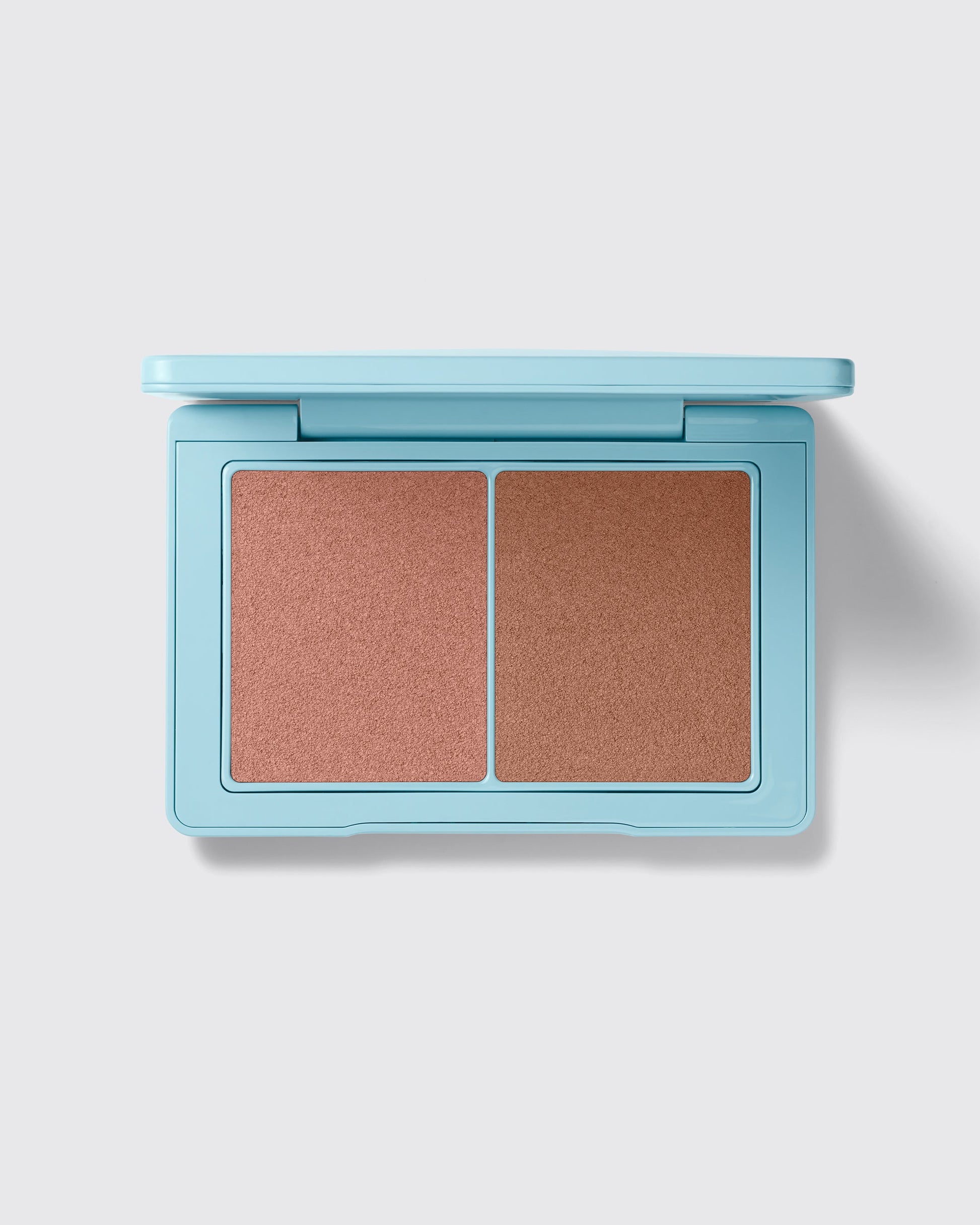 Makeup compact with two brown shades on a light gray background