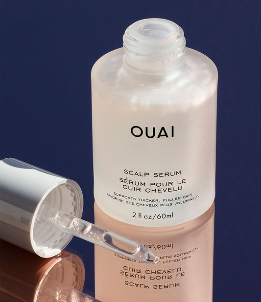 Frosted glass bottle of scalp serum with clear dropper on glossy surface, luxurious texture