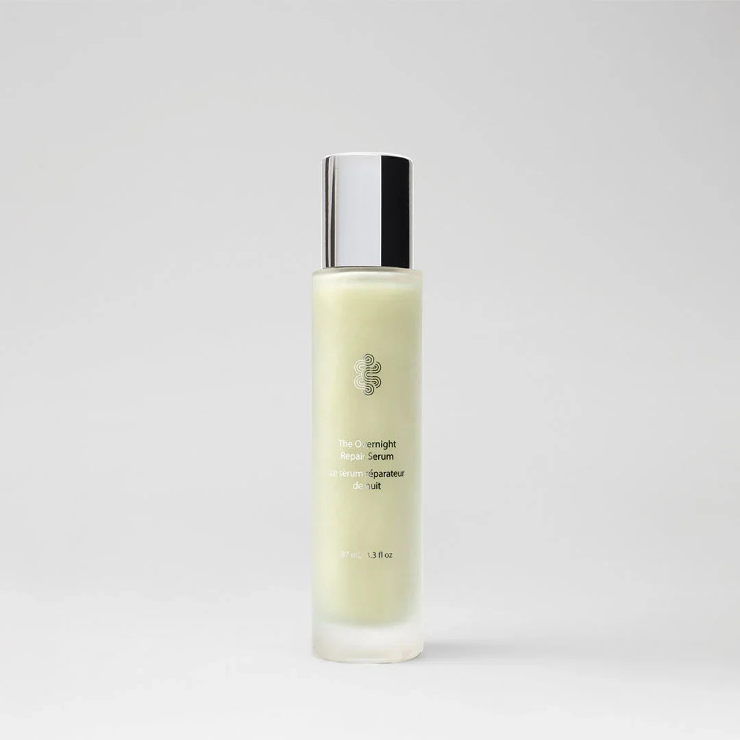 Luxurious frosted bottle of The Overnight Repair Serum with silver cap on a grey background