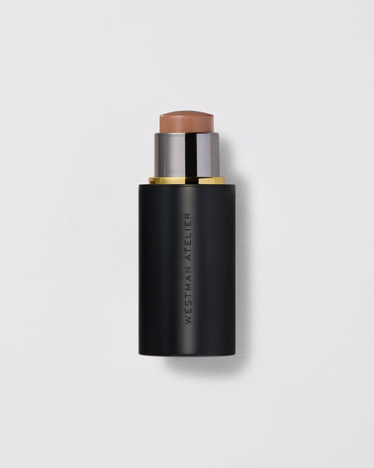 Luxury cream contour stick in nude taupe shade with sleek black and gold packaging.