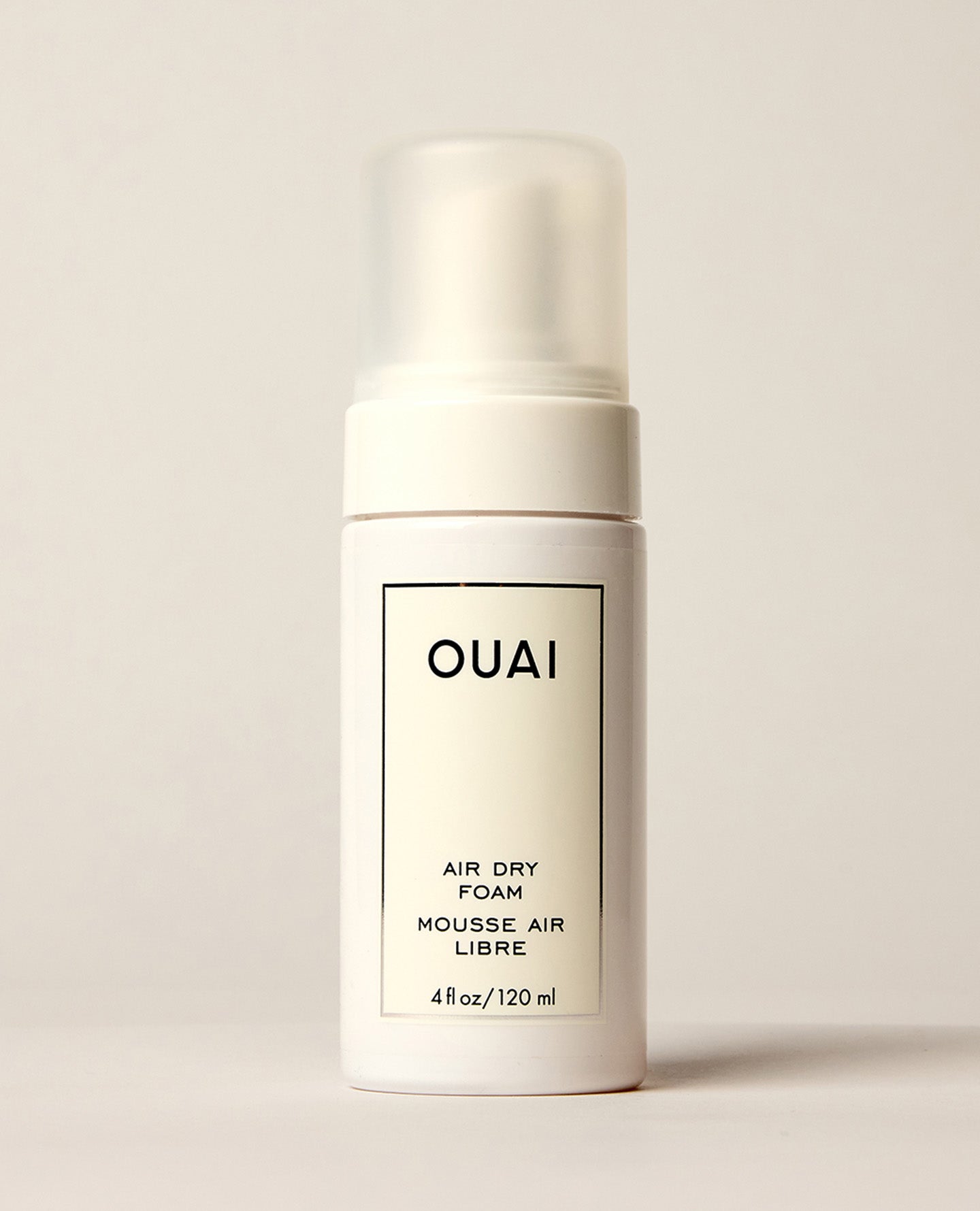 OUAI Air Dry Foam 4 fl oz white pump bottle on neutral background.