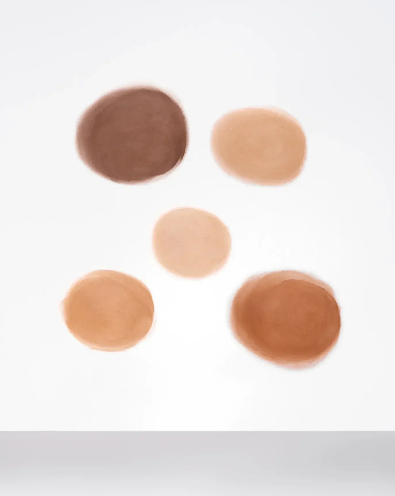Five creamy, dewy blush swatches in varying nude and brown shades on a white background.