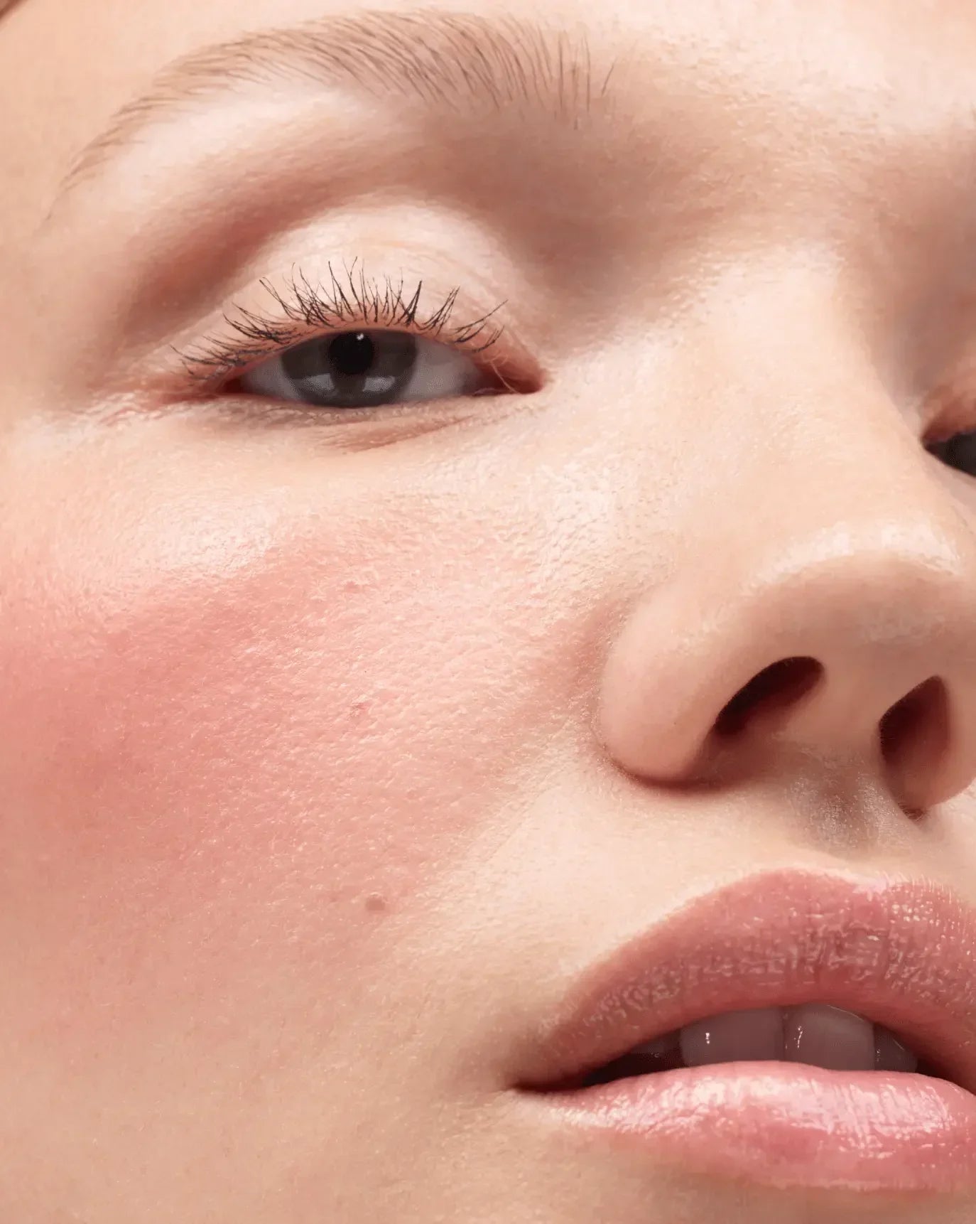 Close-up of a cheek with soft pink blush and dewy, radiant skin texture