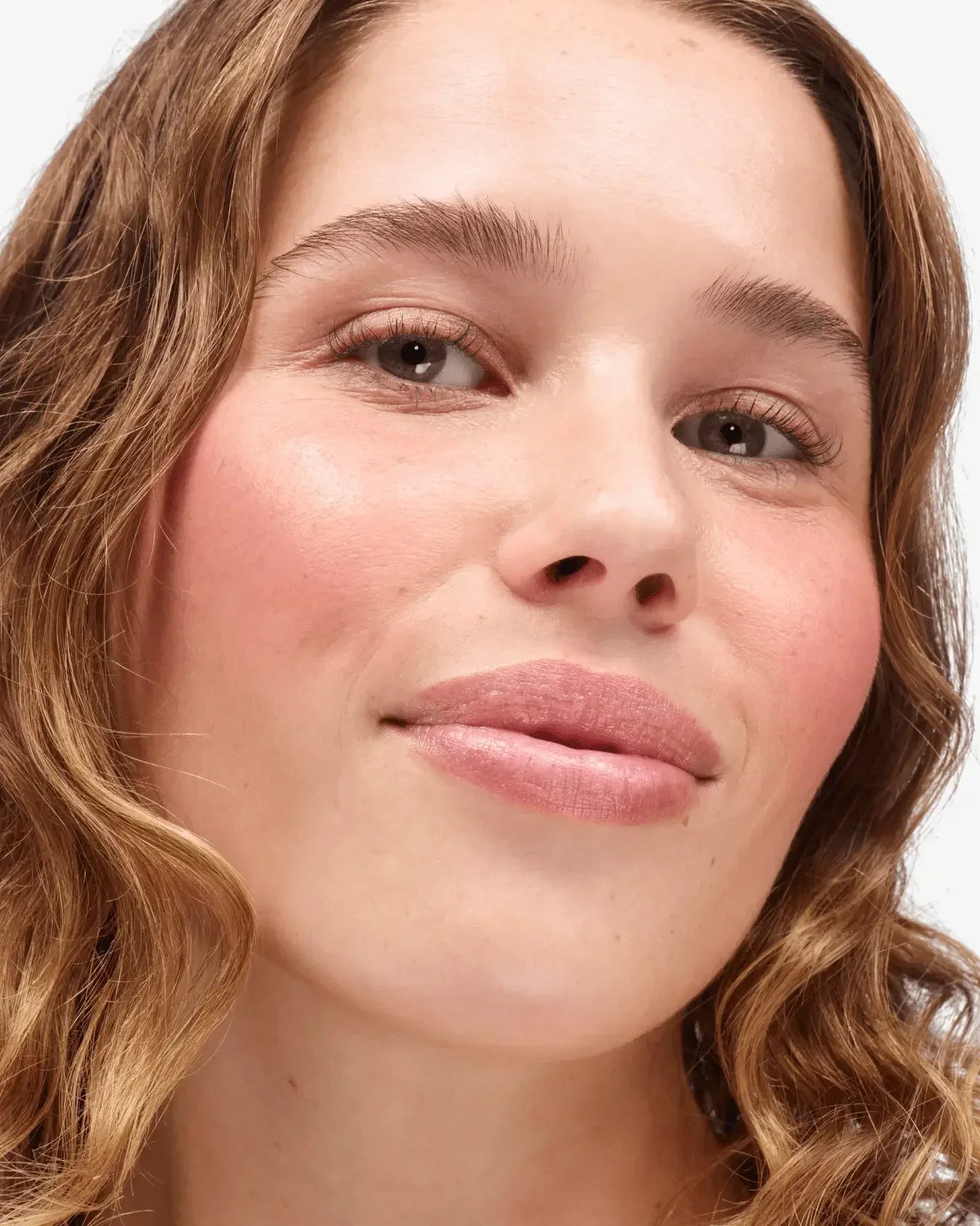 Woman with rosy cheeks and creamy blush, dewy finish, natural makeup look